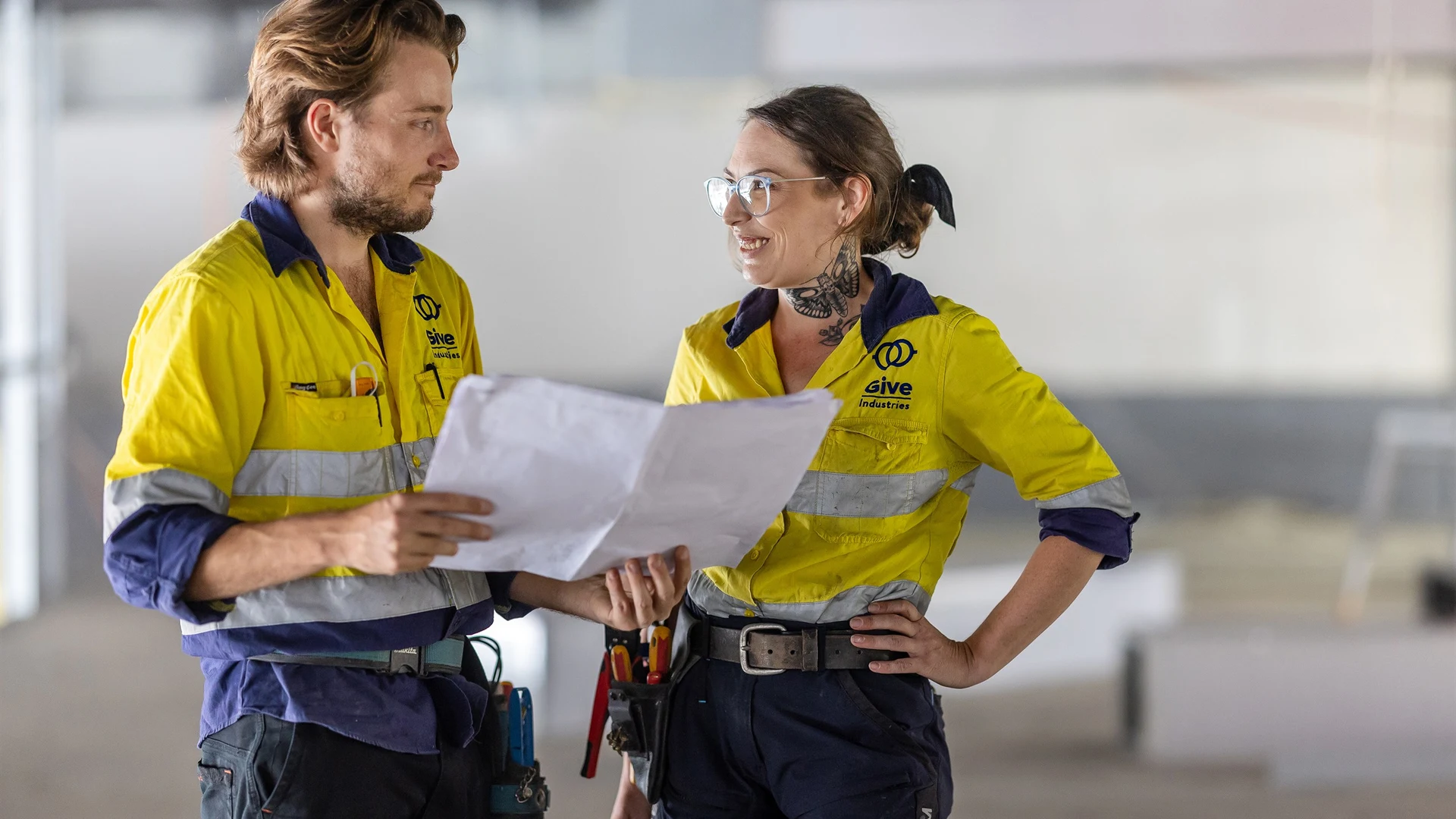 Give Industries electricians discussing plans on a commercial site